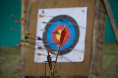 Colorful archery arrows in close up and unfocused target board in background
