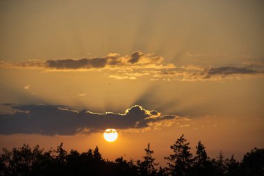 Gökyüzü kahverengiyle kırmızının çarpıcı bir karışımıdır. Parlak turuncu, sarı ve pembe bir ışık tarafından aydınlatılır.
