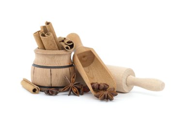 Tarçın çubuklarıyla dolu ahşap kase ve beyaz arka planda izole edilmiş yıldız anasonlu ahşap kepçe.