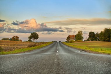 Ufka doğru uzanan beyaz bir çizgiyle asfalt yolu alıyoruz. Akşam güneşinin altın saatiyle aydınlanıyor.