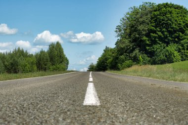 Çevresindeki yemyeşil alana kadar uzanan, merkezini işaretleyen beyaz bir çizgiyle, iyi döşenmiş, dolambaçlı yol.