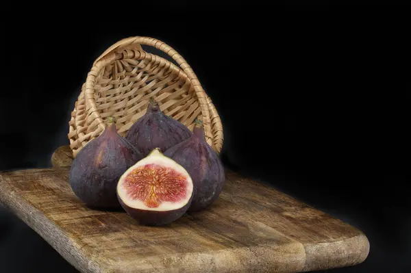 Figs whole and sliced in half near wicker basket present, adding to the homely, rustic vibe of the image