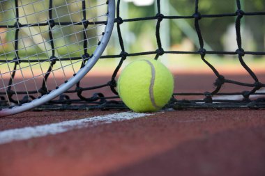 Siyah ağlı tenis sahnesi, beyaz çizgili top ve düşük açılı raket.