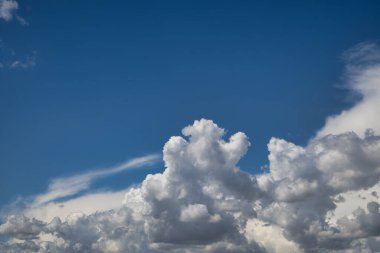 Ufuk boyunca yayılan büyük şişkin bulutlarla dolu gökyüzü, parlak güneş tarafından aydınlatılan bulutların çok azı, gökyüzünde yumuşak bir parıltı oluşturur.