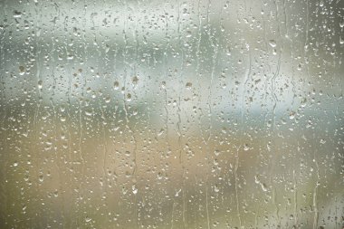 Droplets precipitating from a drizzle outside scattered across a window. Tranquility and solitude often associated with rainy days clipart