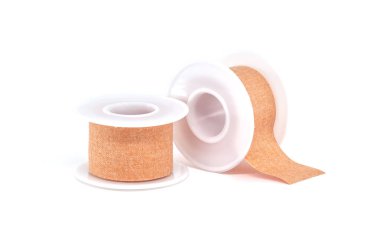 Beyaz arka planda iki rulo cerrahi yapışkan sıva, tıbbi malzemeler.