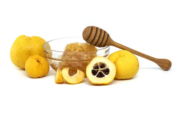 stock image Glass with honey surrounded by vibrant quince fruits, both sliced and whole isolated on white background, full depth of field