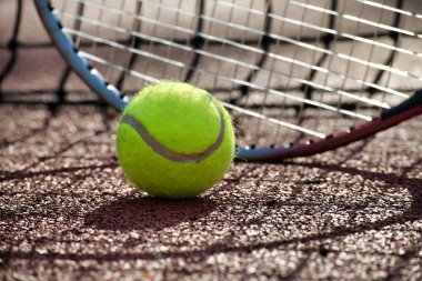 Tenis topu ve raketi kil sahada yaklaş. Spor, spor ve tenisle ilgili konular için ideal.