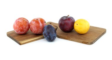 Tahta kesme tahtasındaki taze, renkli erikler canlı meyve çeşitliliği ve sağlıklı beslenme konsepti sergiliyor.