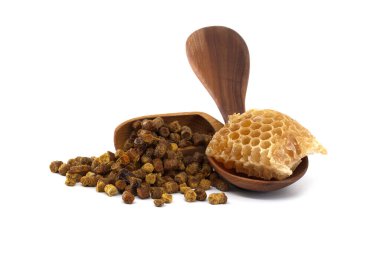 Arı polen granülleri ve bal peteği beyaz arka plana karşı ahşap bir kepçe ve kase üzerinde sergilenir, doğal sağlık avantajlarını vurgulayarak