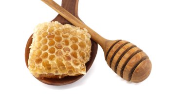 Bal kovanı ve tahta kaşığın üzerindeki bal peteğinin yakın çekimi. Doğal tatlılık ve organik gıda kavramları için mükemmel..