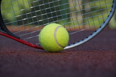 Tenis topu ve raketi kil sahada yaklaş. Spor, spor ve tenisle ilgili konular için ideal.