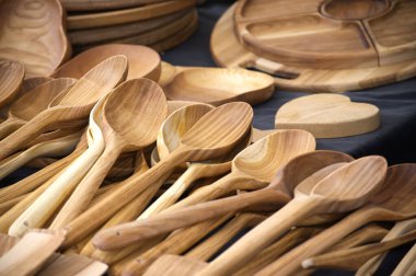 Masada gösterilen, içinde kaşıklar ve kesme tahtaları olan ahşap mutfak aletleri koleksiyonu. Kırsal ya da modern mutfaklarda yemek, servis ya da dekor için ideal..