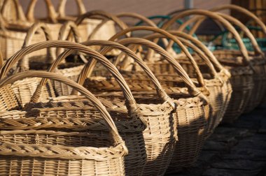 Hasır sepetlerin çeşitli çeşitleri, güneşli bir açık hava pazarında geleneksel zanaatkarlığı ve çevre dostu materyalleri vurguluyor..