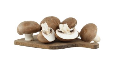 Bir grup taze düğme mantarı ahşap bir kesim tahtasına güzelce yerleştirilmiş, doğal dokularını ve topraksı tazeliklerini sergiliyorlar, yemek pişirmek ve yemek pişirmek için mükemmel.