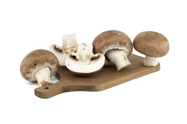 Tahta kesme tahtasına yerleştirilmiş taze kahverengi mantarlar beyaz arka plana karşı doğal dokularını ve renklerini sergiliyor. Mutfak ve yiyecekle ilgili kavramlar için ideal.