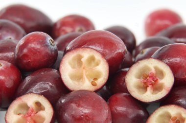 Close-up image showcasing fresh red cranberries highlighting their juicy texture and vibrant color. The halved cranberries reveal detailed seed structures evoking sense of freshness and natural health clipart