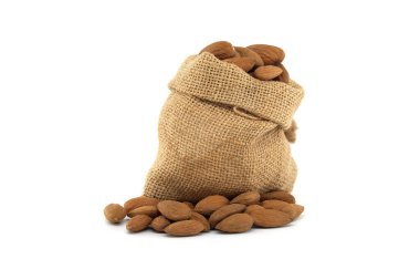 Beyaz arka planda taze bademlerle çevrili bir çuval bembeyaz, sade ve sağlıklı bir yaşam tarzını çağrıştırıyor.