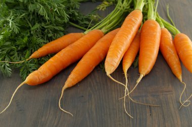 Canlı, yeşil bluzlu yeşil uçlu, ahşap arka planda dinlenen taze havuçlar sağlıklı yemek ve çiftlikten sofraya temalar için mükemmel..