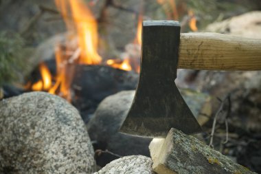El baltası yakacak odunları çatırdayan bir kamp ateşinin yanında kırıyor, ormanın huzurlu güzelliği ile çevrelenmiş, sıcacık bir ortamda sıcaklık ve ışık yaratıyor