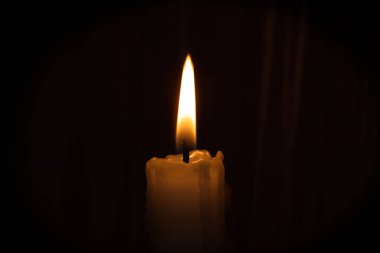 Tek bir mum, karanlık bir arkaplanda parlak bir şekilde yanar. Sıcak ve davetkar bir ortam yaratır. Huzur ve huzur..