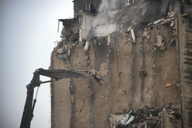 Endüstriyel yıkım, yüksek katlı bir yapıyı sökmek için ağır makineler kullanıldığını gösteriyor.