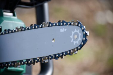 Keskin dişlerini ve karmaşık zincir dizaynını gösteren elektrikli testere bıçağının yakın çekim görüntüsü. Odaklanma aracın mekaniğine odaklanır.