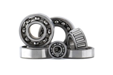 Beyaz arka planda top ve paten de dahil olmak üzere çeşitli metal bilye türleri. Endüstriyel makineler için mekanik bileşenler sürtünmeyi azaltır ve düzgün bir hareket sağlar.
