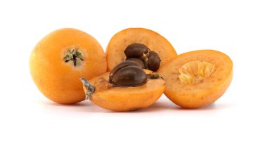 Olgun lokuatlar, Eriobotrya japonica olarak da bilinir, bütün ve ikiye bölünmüş, tohumlarını ortaya çıkarır, temiz beyaz bir arkaplanda düzenlenir, basit ama canlı bir kompozisyon oluşturur.