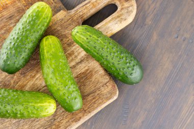 Tahta kesme tahtasının üzerinde salatalar, sandviçler ya da diğer aşçılık ürünlerinde dilimlenmeye ve kullanılmaya hazır bir sürü taze salatalık var.