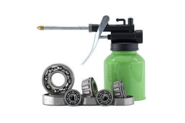 Yeşil bir yağ tenekesi, yağ ve bilye düz beyaz bir zemine dizilmiş. Araçlar makineler içindir..