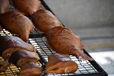 Tel askıda dinlenen tütsülenmiş balıklar renk ve dokularını sergiliyorlar. Mükemmel bir mutfak zevki yakalar, menü konseptleri, mutfak vitrinleri ya da gurme yemek deneyimleri için ideal..