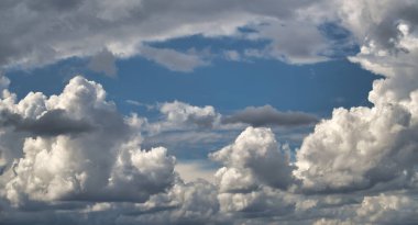 Mavi gökyüzünün kabarık kümülüs bulutlarının arasından bakıp durgun ama güçlü bir atmosfer oluşturduğu dramatik bulutlar..