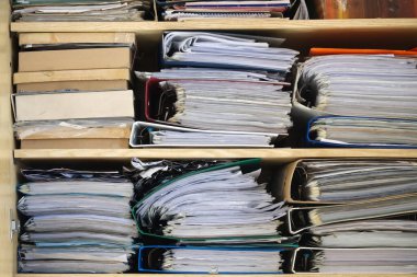 Organizasyon kavramını gösteren doküman, dosya ve klasörlerle dolu ahşap bir dolabın yakın plan fotoğrafı..