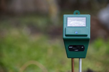 Açık hava bahçesindeki yeşil bir nem ölçer, sağlıklı bitkileri beslemek için toprak nemi ve ışığı gözlemler. Bahçıvanlar ve peyzajcılar için sulama ve toprak koşullarını yöneten pratik bir araç.