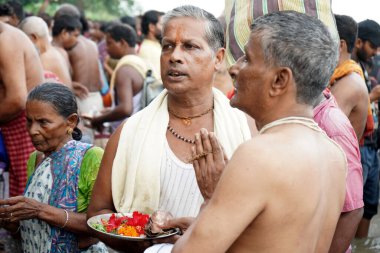 Hindu priest helps to Performing Tarpan during Mahalaya at Babu Ghat clipart
