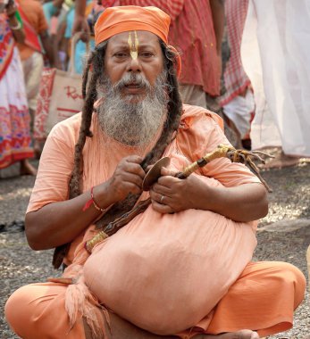 14th October 2023, Babughat, Kolkata, West Bengal, India. Hindu Sadhu Seated on Ground Playing Cymbals at Religious Festival