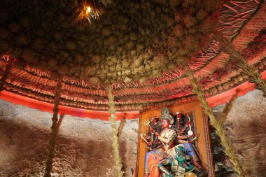 Conceptual Durga Idol in Rustic Straw Hut Pandal with Red Lighting