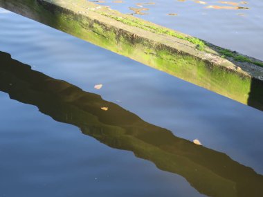 a wooden bar or beam crossing the water makinga shadow