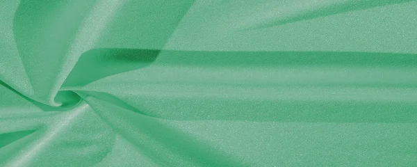 Stock image green silk. Smooth elegant green luxury silk fabric can be used as abstract background with copy space, close up. colorful texture