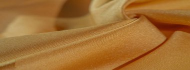 Sarı renkli ipek kumaş. Renkli ipek kumaşın dokusu arka plan olarak kullanılabilir