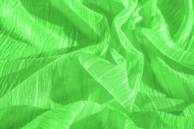 İpek kumaş. Yeşil kırışık kumaş dokusu. Yeşil buruşuk, dalgalı yüzey dokusu. Yakın çekim, yumuşak odaklanma. arkaplan, kalıp