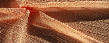 İpek kumaş. Kahverengi kırışık kumaş dokusu. Kahverengi buruşuk, dalgalı yüzey dokusu. Yakın çekim, yumuşak odaklanma. arkaplan, kalıp