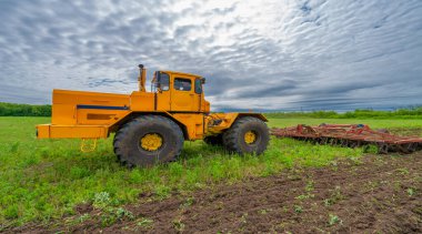 Bahar fotoğrafçılığı, ziraat makineleriyle manzara, bir traktör tarlayı sürüyor, tarlayı sürüyor, kuşlar ekilebilir arazinin üzerinde uçuyor.