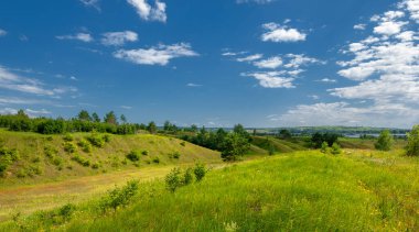Yaz manzarası, nehir taşkınları, pitoresk kıyılar, kır çiçekli parlak yeşil çimenler, beyaz bulutlu mavi gökyüzü, ılık yaz günleri.,