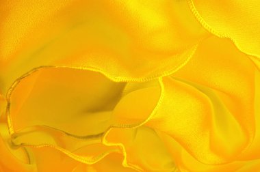 Dalgalı boruları olan sarı ipek organza. Kumaşın kenarındaki sınır. Soyut arkaplan. doku deseni. İpek organzanın narin bir açık dokuması vardır. Dalga arkaplanı. Boşluğu kopyala