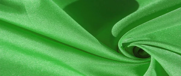 Silk fabric, green forest. Pleats in silky green fabric, close-up, full frame. Texture, background, pattern