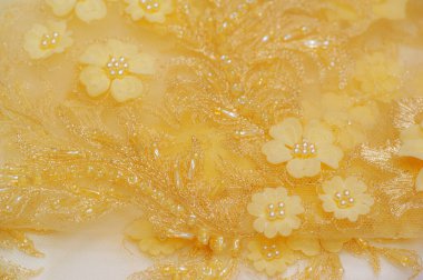 Dantelli desenli altın sarısı bir arka plan. Kartpostal, poster, doku ve duvar kağıdı yapmak için ideal. Herhangi bir tasarım projesine klasik ve zarif bir görünüm verir.