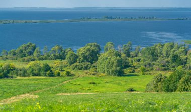 Yaz manzarası. Dünyanın Avrupa bölgesindeki bir nehir. Güneşli sıcak bir gün. Yeşil ağaçlar, çimenler. Mavi gökyüzü küçük bir bulut örtüsüyle.