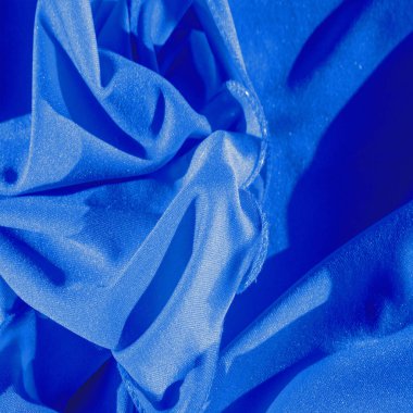 Mavi ipek. Pürüzsüz mavi lüks ipek kumaş, yakın plan fotokopi alanı ile soyut bir arkaplan olarak kullanılabilir. Renkli doku